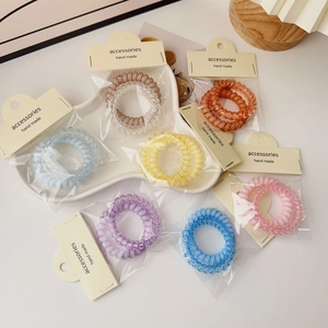 Colorful spiral telephone cord hair ties in assorted pastel shades in a heart ceramic dish