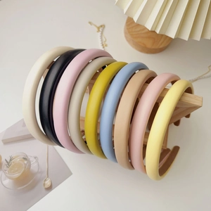 Multiple colorful padded fabric headbands displayed on a wooden stand in a warm setting