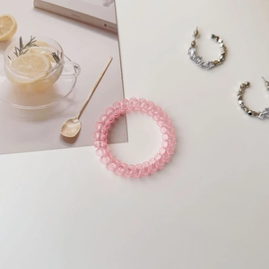 Detailed view of a semi-transparent pink spiral hair coil on a clean minimalist background