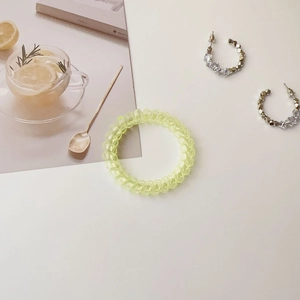 Close-up of a translucent yellow spiral telephone cord hair tie on a white background