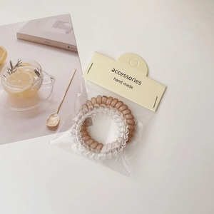 Macro detail of clear and brown spiral hair ties on an aesthetic card packaging