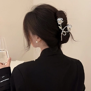 Detailed close-up of a silver rose flower hair claw clip styling a low bun hairstyle