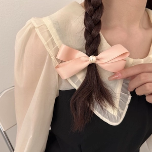 Fermaglio per capelli a fiocco in raso rosa con perla su un'acconciatura a treccia