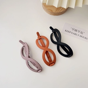 Close-up of matte infinity-shaped hair clips in pink, caramel, and black finishes