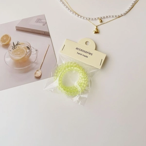 Détail de chouchous spirales vert clair dans leur emballage transparent avec carte