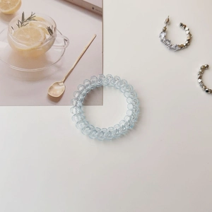 Macro detail of light blue spiral hair tie and silver earrings with crystal inlay