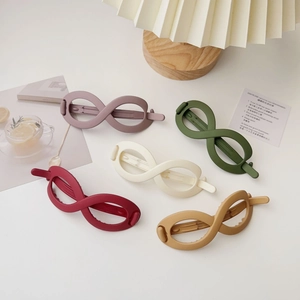 Detailed view of five matte infinity hair clips in Morandi colors on a minimal desk