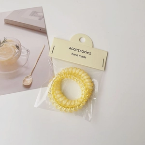Close-up of yellow spiral hair ties in premium packaging with lemon-themed backdrop