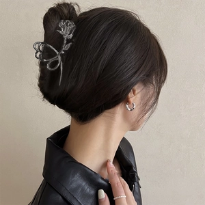 Detailed close-up of a silver rose metal hair claw clip worn by a model in a French style