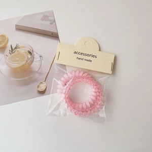 Pink spiral telephone wire hair ties in minimalist handmade card packaging
