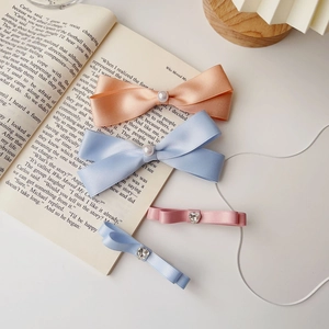 Dettaglio di fermagli per capelli a fiocco con perle e strass su un libro aperto
