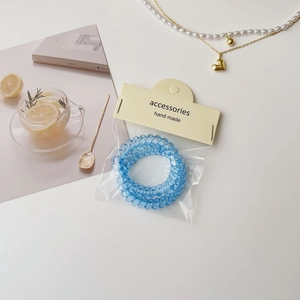 Vue détaillée d'un élastique spirale bleu dans son emballage sur une table blanche épurée