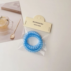 Blue spiral telephone wire hair ties set on a bright minimalist background with accessories