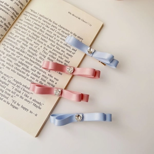 Dettaglio di fermagli per capelli in raso con strass a cuore su un libro aperto