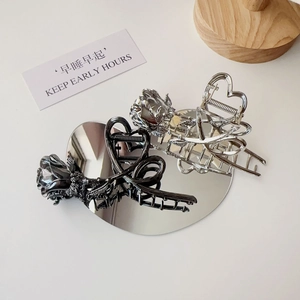 Close-up of metallic rose hair claws in silver and black gunmetal on heart mirror