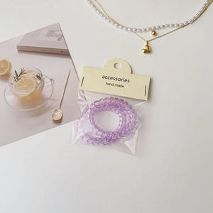 Lot de deux élastiques spirales violets transparents sur emballage carton minimaliste