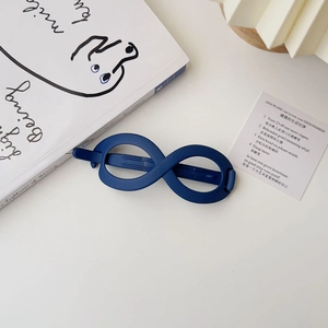Macro detail of navy blue matte infinity hair clip with a minimalist textured finish