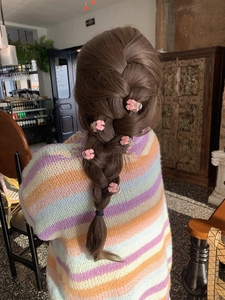 Close-up of pink bow hair clips styled on a braided hairstyle with a pastel sweater
