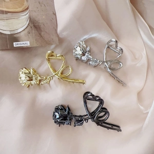 Detailed view of rose flower metal hair claws in gold, silver, and black on silk