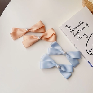 Dettaglio di fermagli per capelli a fiocco in raso rosa e blu con perle su un libro