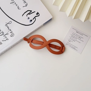 Detailed view of matte infinity shaped hair clip in brick red on a minimalist background