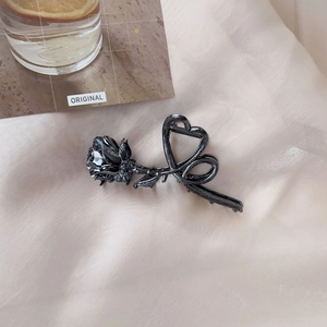 Detailed close-up of a vintage black metal rose hair claw clip on silk fabric