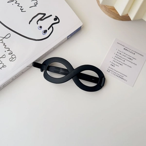 Detail of infinity hair clip with matte black finish on a minimalist background
