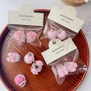 Detail shot of mini pink hair clips with rose and bow designs in gift packaging