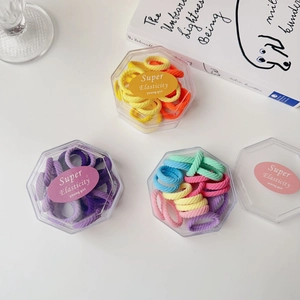 Detailed view of colorful high-elasticity hair ties in hexagonal boxes on a white desk