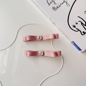 Dettaglio di fermagli per capelli in raso rosa con cristalli a forma di cuore