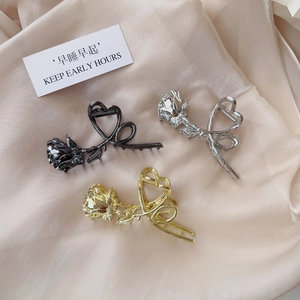 Detail of rose hair claw clips in black, silver and gold finishes on silk background