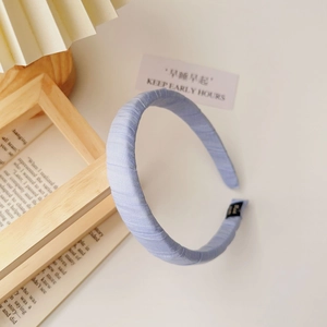 Detail of light blue ribbed fabric headband with soft wrapped ends and brand label