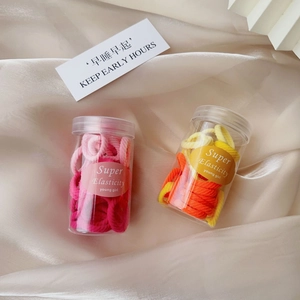 Colorful elastic hair ties in transparent jars on elegant beige silk fabric background