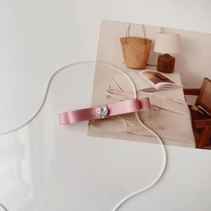 Dettaglio del fiocco in raso rosa con cristallo a cuore su sfondo bianco pulito
