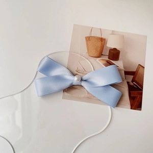 Dettaglio del fermaglio per capelli con fiocco in raso azzurro e perla tonda bianca