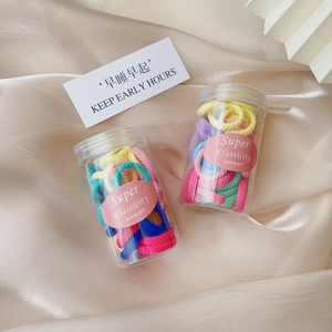 Detailed macro of pastel rainbow elastic hair ties stored in clear cylindrical jars