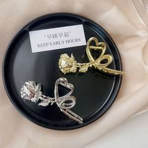 Detail of elegant gold and silver metal rose hair claws with heart-shaped handle design
