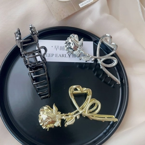Close-up of three vintage metal rose hair claws in black, gold and silver finishes