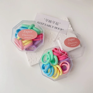Detail of candy-colored high-elasticity hair ties in a clear hexagonal storage box
