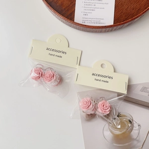 Detail showing pink rose hair clip with matte texture on cream handmade gift packaging