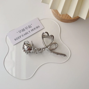 Detailed close-up of a silver vintage metal rose hair claw clip with heart-shaped handle