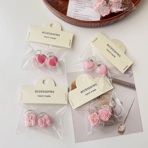 Detail view of pink bow and camellia mini hair claws in clear packaging on a white tray