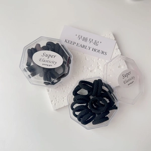 Detailed view of high elasticity black thick hair ties in a clear hexagonal storage box