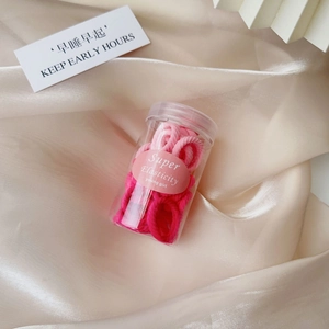 Jar of high elasticity pink hair bands set on champagne satin fabric with card detail