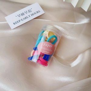 Detailed macro view of colorful elastic hair ties in a clear bottle on champagne satin