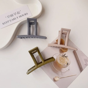 Detailed view of square acrylic hair claws in olive, blue, and nude on a white tray