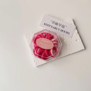 Close-up of high elasticity hair ties in a clear gift box on a white textured stone base