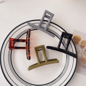 Close-up of four rectangular acrylic hair claws in assorted colors on a ceramic plate