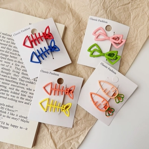 Détail de barrettes à cheveux en métal mat avec formes de nœud et couleurs acidulées
