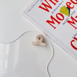 Detail of a beige handmade acetate mini hair claw clip resting on an acrylic board